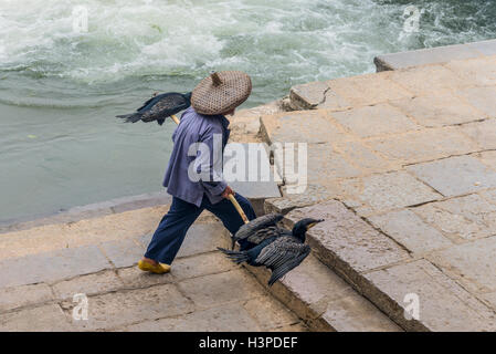 Cormorant fisherman goes to his ancient bamboo raft on the Li River in Yangshuo, Guangxi, Сhina Stock Photo