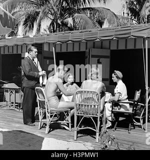 1930s THREE WOMEN ONE MAN DINING BY BEACH WAITER TAKING ORDER NAUTILUS HOTEL CABANA CLUB MIAMI BEACH FLORIDA USA Stock Photo