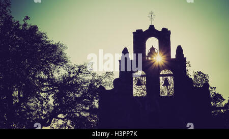 Spanish Mission Espada church bells in silhouette as the sun sets behind mission in San Antonio, Texas Stock Photo