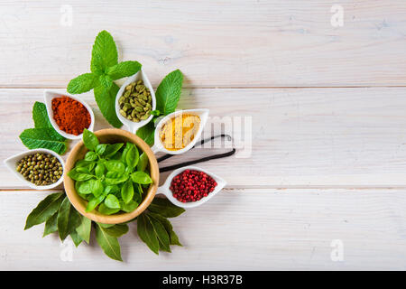 Fresh and colorful herbs and spices assortment on a white wooden background