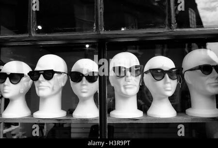 Sunglasses displayed on polystyrene mannequin heads in a shop window. Stock Photo