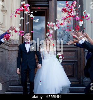 Guests Throwing rose petals Over Bride And Groom At Wedding Stock Photo