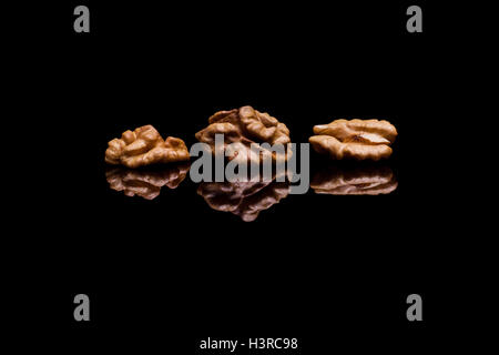 Three walnuts isolated on black reflective background Stock Photo