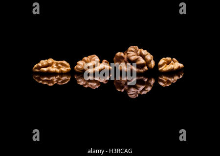 Four walnuts isolated on black reflective background Stock Photo