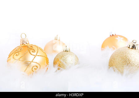 Golden Christmas baubles on a soft feathery surface with a white background. Stock Photo