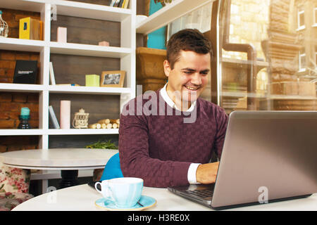 Happy young man smiling and works on his laptop Stock Photo