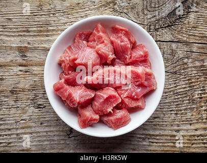 White bowl of raw diced beef meat on wooden table, top view Stock Photo