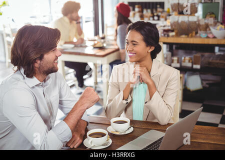 Smiling man and woman using a laptop while having cup of coffee Stock Photo