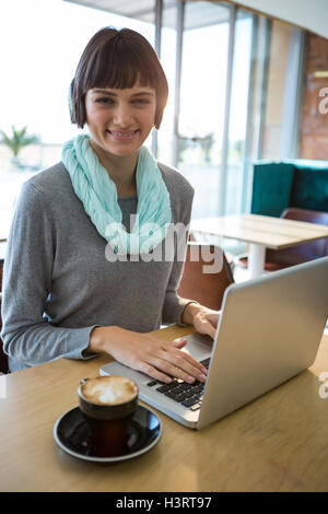 Smiling woman using laptop while having coffee Stock Photo