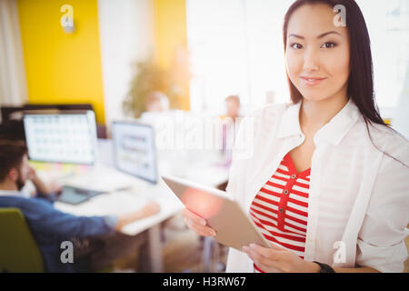 Portrait of happy businesswoman using tablet computer at creative office Stock Photo