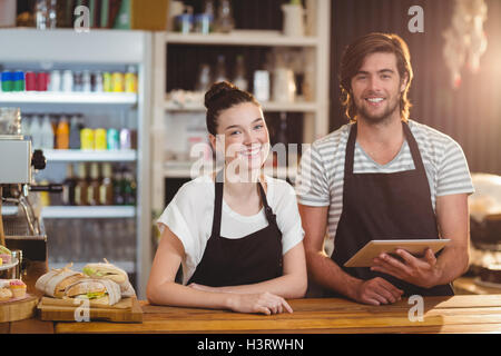 Smiling waiter and waitress using digital tablet at counter Stock Photo
