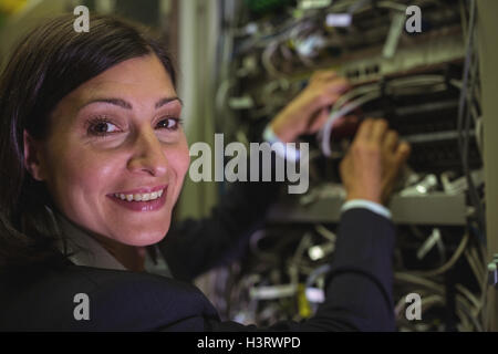 Portrait of technician checking cables in a rack mounted server Stock Photo