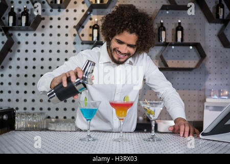 Bartender pouring cocktail into glasses Stock Photo