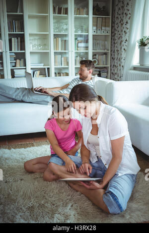 Mother and daughter sitting on floor and using digital tablet Stock Photo