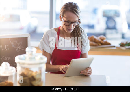 Waitress sitting at table and using digital tablet Stock Photo