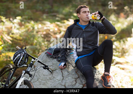 Male biker drinking water in forest Stock Photo