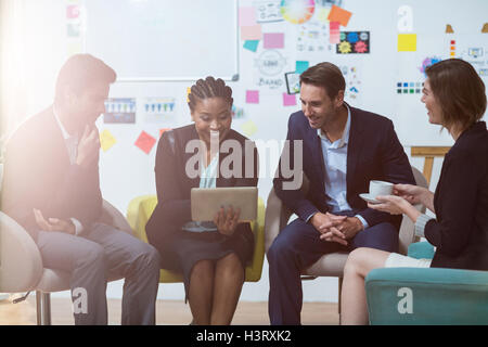 Businesswoman discussing with colleagues over digital tablet Stock Photo