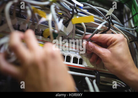 Technician plugging patch cable in a rack mounted server Stock Photo