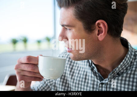 Thoughtful man looking out of the window while having coffee Stock Photo