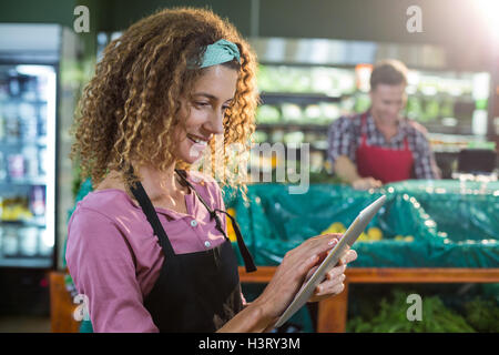 Female staff using digital tablet in organic section Stock Photo