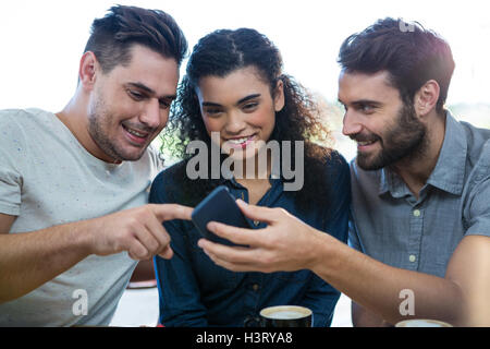 Three friends using mobile phone in the coffee shop Stock Photo