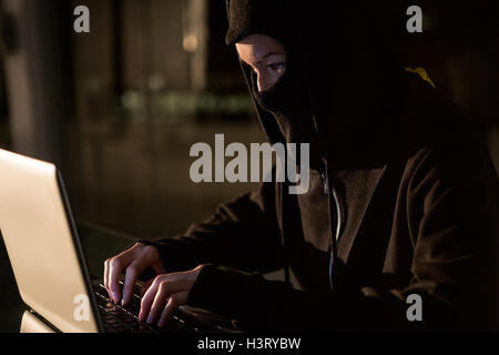 Woman in balaclava using laptop Stock Photo