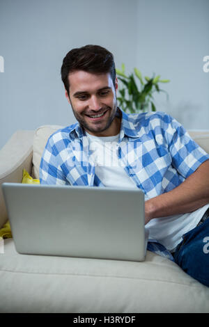 Man using laptop while relaxing on sofa Stock Photo