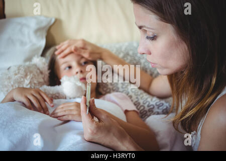 Mother checking daughters temperature on thermometer Stock Photo