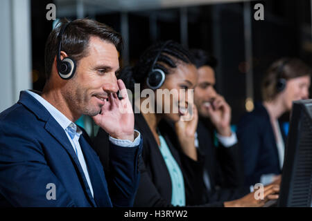 Colleagues with headsets using computer at office Stock Photo