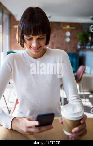 Woman using mobile phone while having coffee Stock Photo