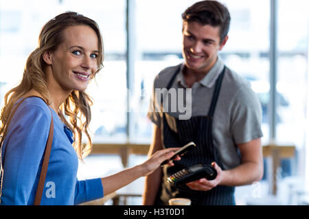 Woman paying bill through smartphone using NFC technology Stock Photo