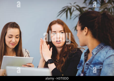 Businesswomen discussing at desk while using digital tablet Stock Photo