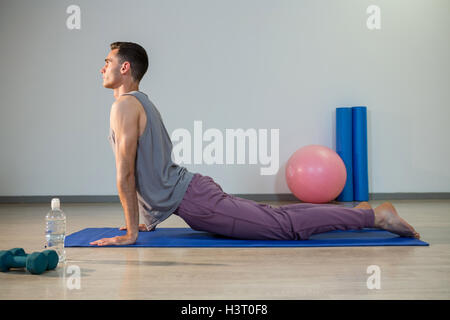 Man doing cobra pose on exercise mat Stock Photo