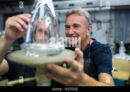 Glassblower and a colleague examining glassware Stock Photo
