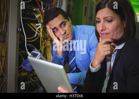 Bored technician looking at colleague while analyzing server Stock Photo
