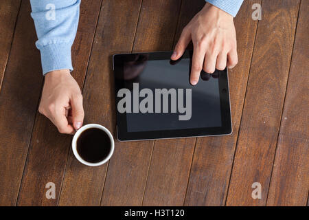 Man using digital tablet while having cup of coffee Stock Photo