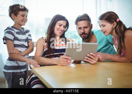 Family using digital tablet while sitting at table Stock Photo