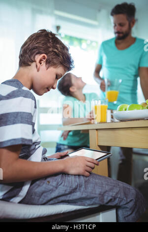 Boy using digital tablet with breakfast on table Stock Photo