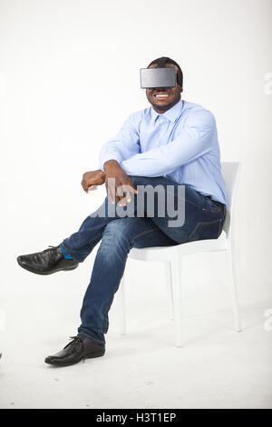 Man sitting on chair and using virtual reality headset Stock Photo