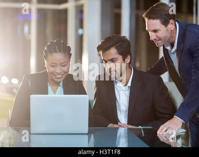 Businesswoman discussing with colleagues over laptop Stock Photo
