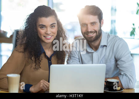 Smiling couple using laptop in caf├⌐ Stock Photo