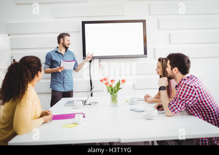 Colleagues listening to executive in meeting at creative office Stock Photo