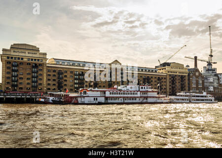 Golden light in the evening reflecting on the River Thames and Butler's Wharf, London, UK, the Dixie Queen paddle steamer in the foreground Stock Photo