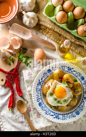 Baked potato with chili and fried egg, fresh young tomatoes and spicy chilli with herbs, great combination of flavours and spicy Stock Photo