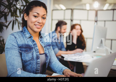 Smiling creative businesswoman using laptop at desk Stock Photo