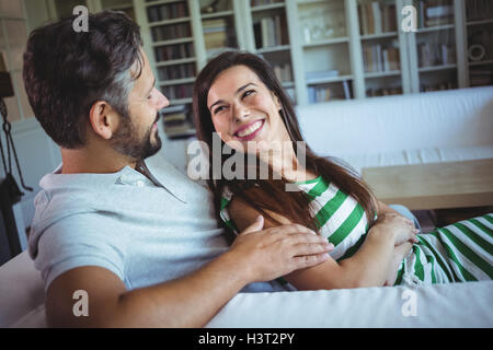 Happy couple lying on sofa in living room Stock Photo