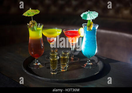 Various cocktail drinks and shot glasses of tequila on serving tray Stock Photo