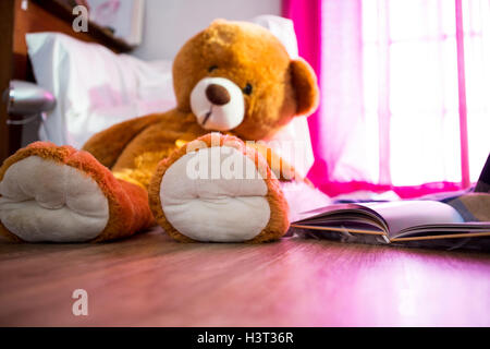 Teddy bear and book lying on wooden floor Stock Photo
