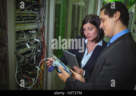 Technician working on personal computer while analyzing server Technicians using digital cable analy Stock Photo