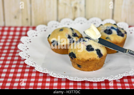 blueberry muffins on white plate with butter on knife Stock Photo